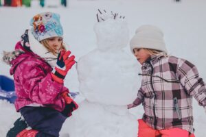 Two children building a snowperson